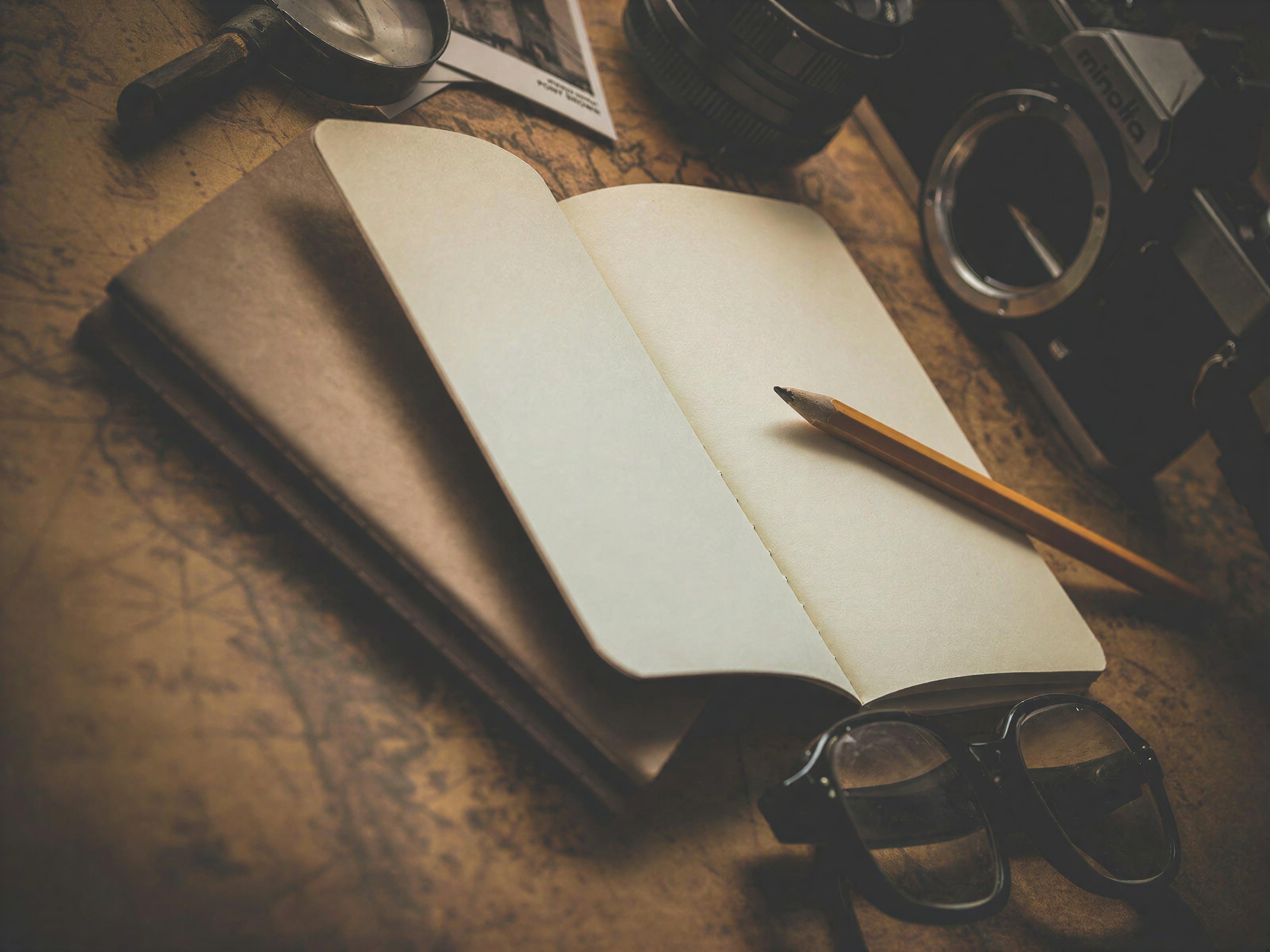 An open notebook and pencil on a wooden desk