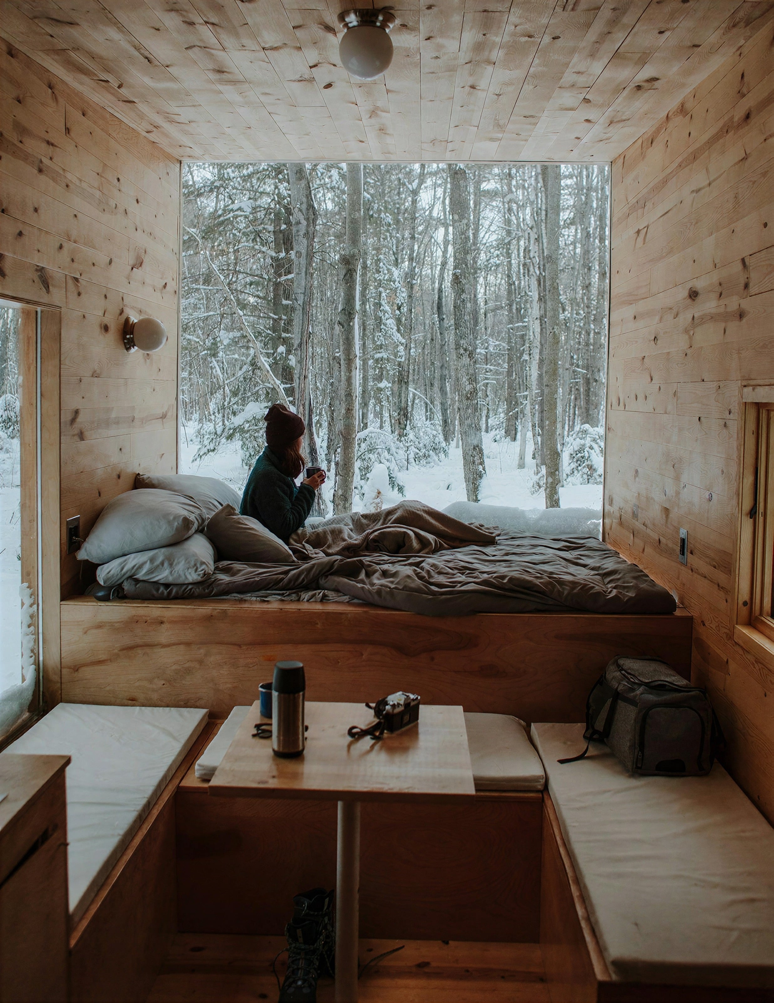 A wood-panelled cabin room with a window onto snowy forest