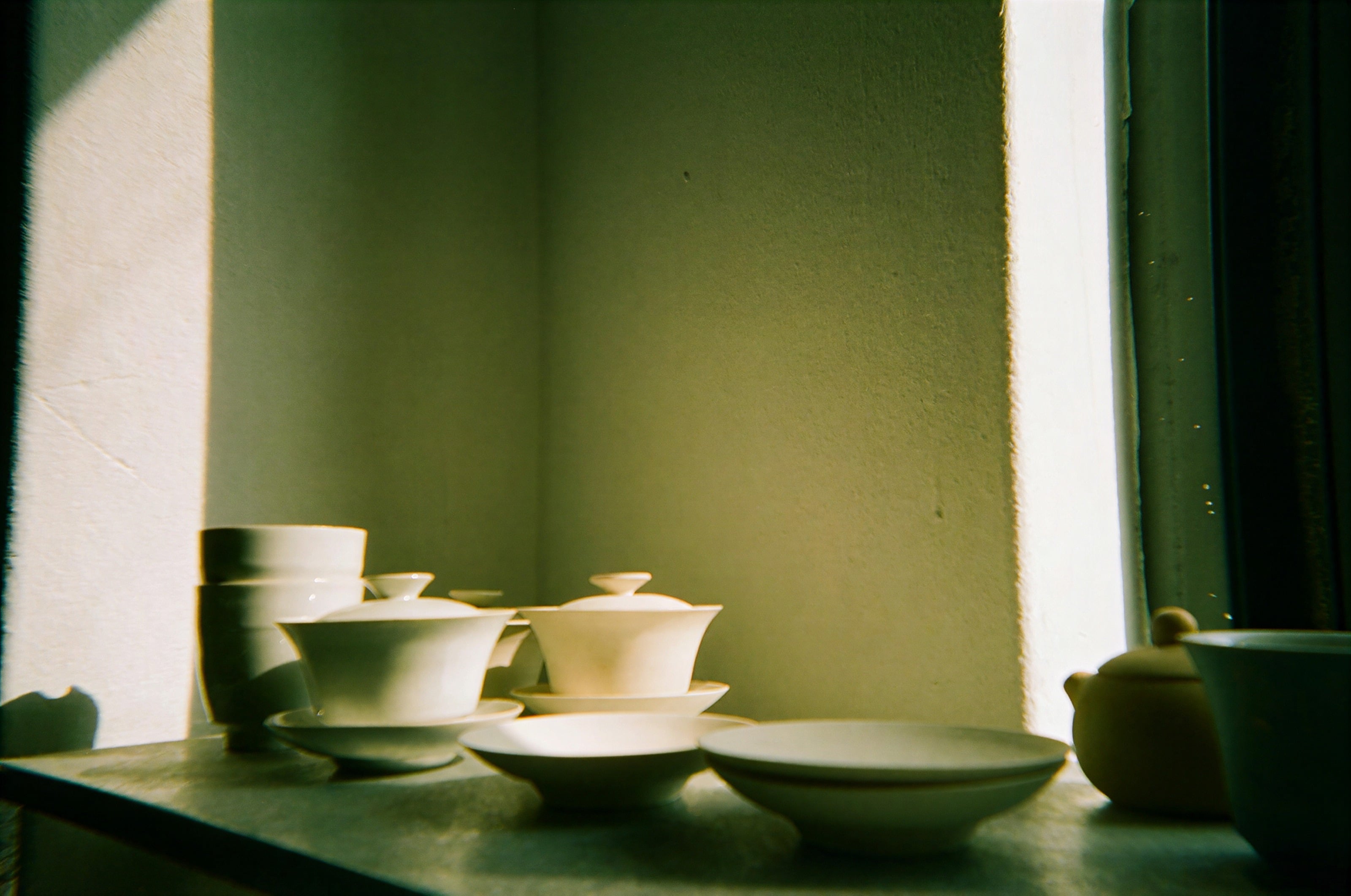 White ceramic tea bowls on a sunlit windowsill