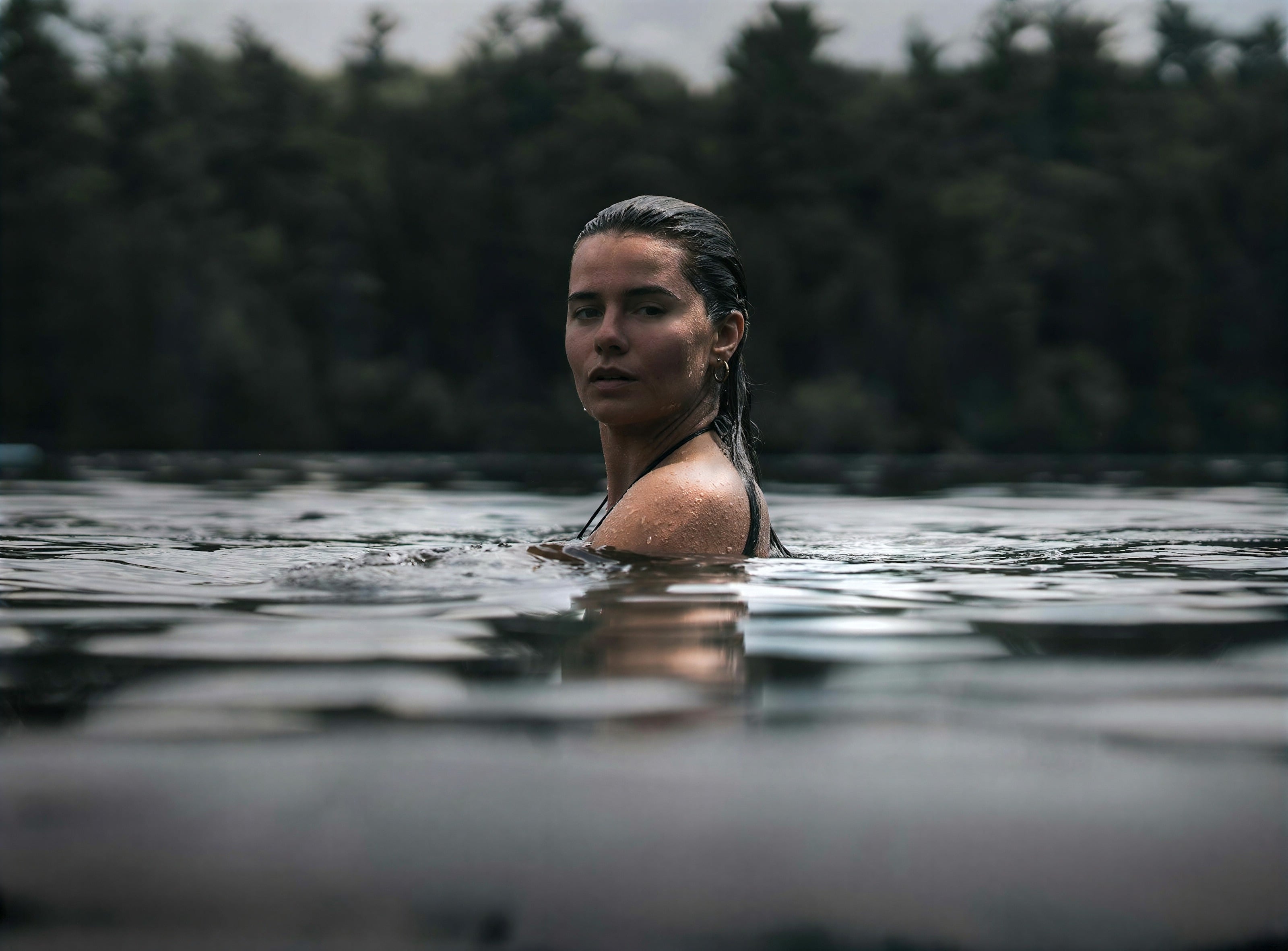A woman swimming in a still forest lake
