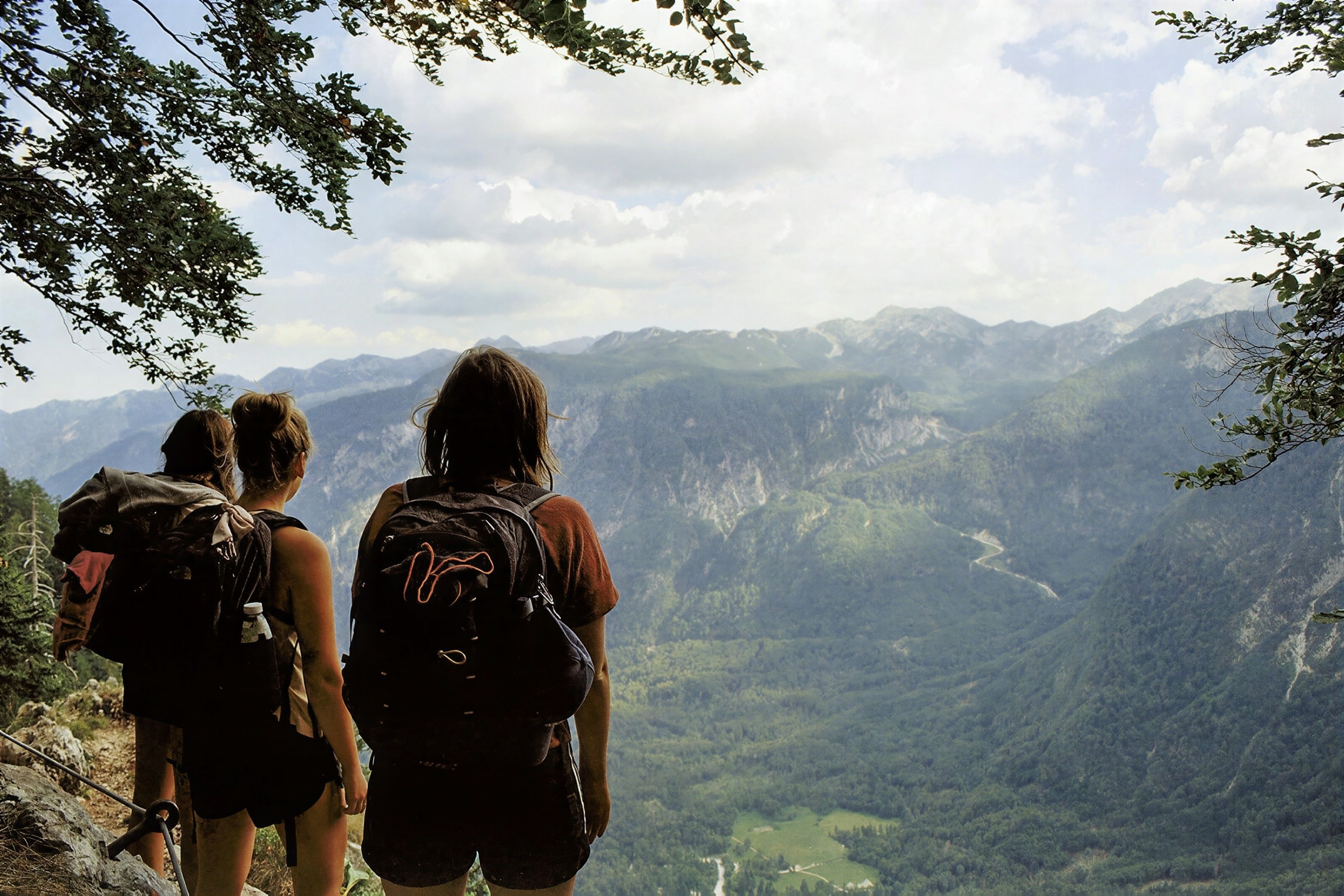 Two hikers with backpacks looking out over a green mountain valley