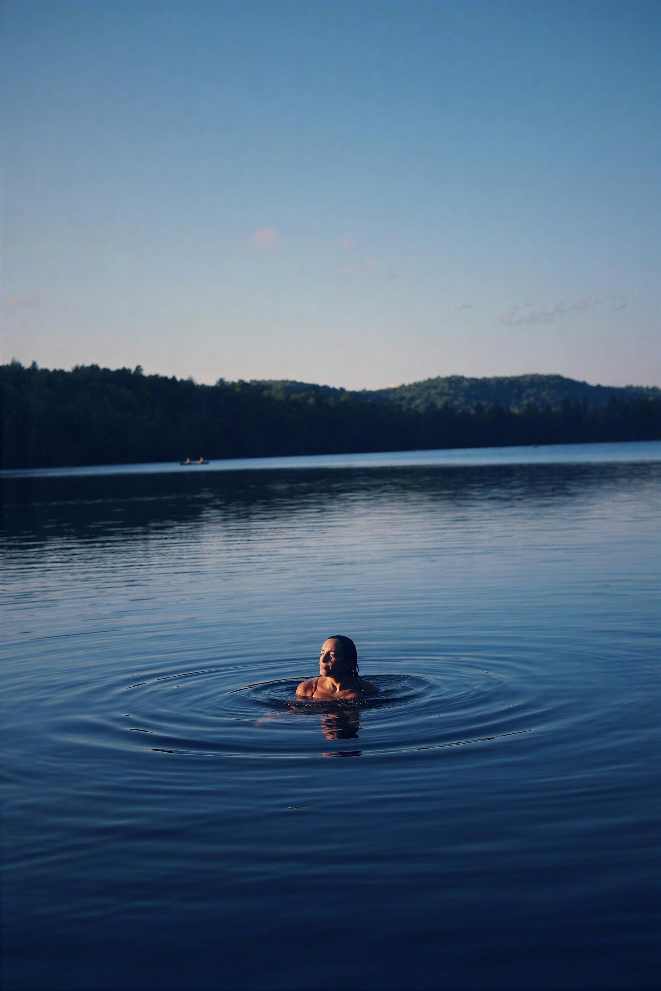 A swimmer alone in a calm blue lake at dusk