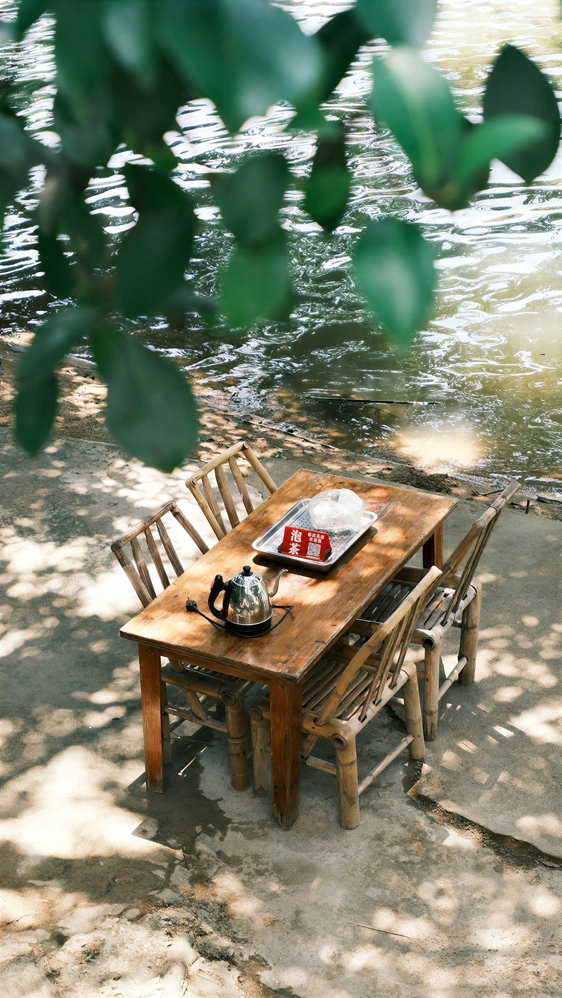 A small wooden table set for tea in dappled shade